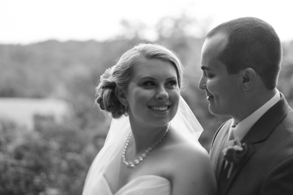 bride facing smiling groom on overlook with hayfield in the background