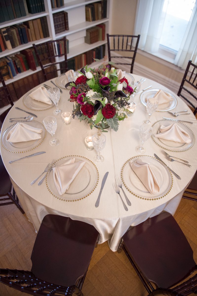 Clear charger plates with white linen tablecloth, add a bold red centerpiece