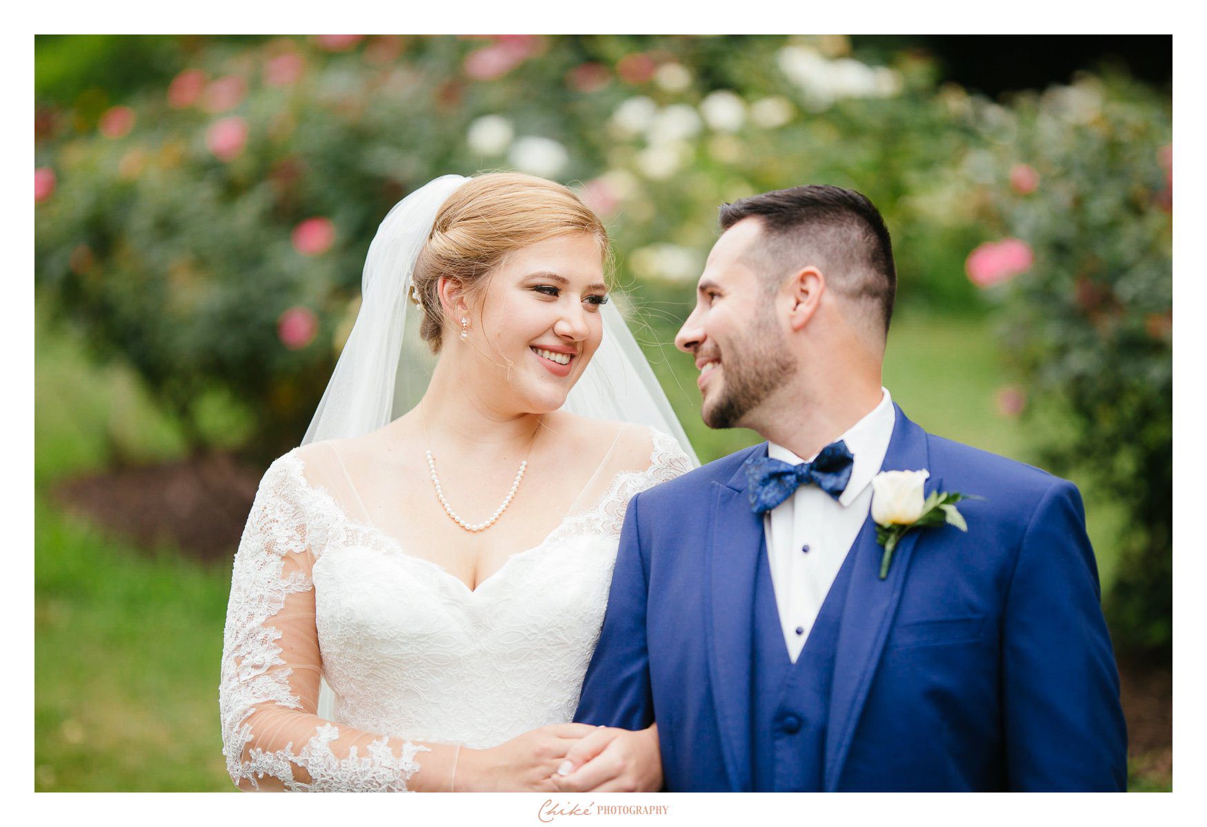 bride and groom looking into each others eyes by the roses