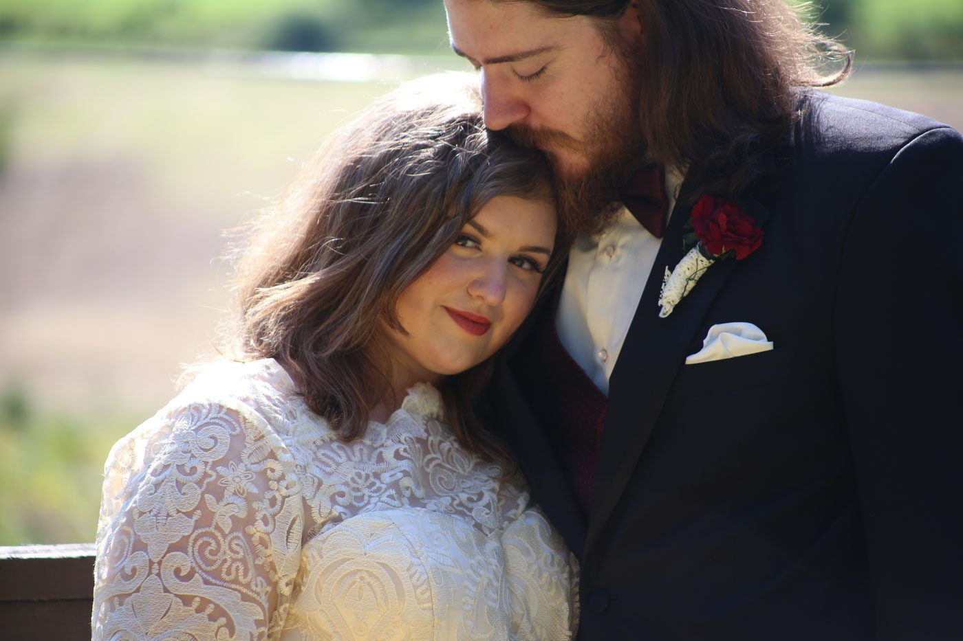 groom kissing brides head tucked on his shoulder